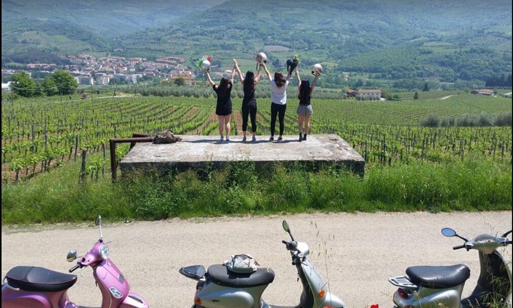 Riders celebrating above the Chianti vineyards with Vespas